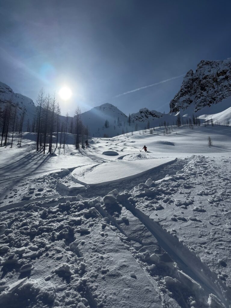 Heliski tracks in fresh untouched powder snow on a sunny high-altitude slope