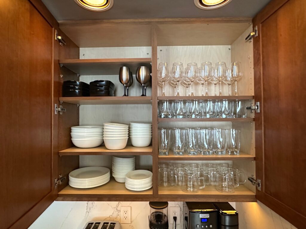Pinehaven cabin kitchen cabinet stocked with glasses and plates for eight guests