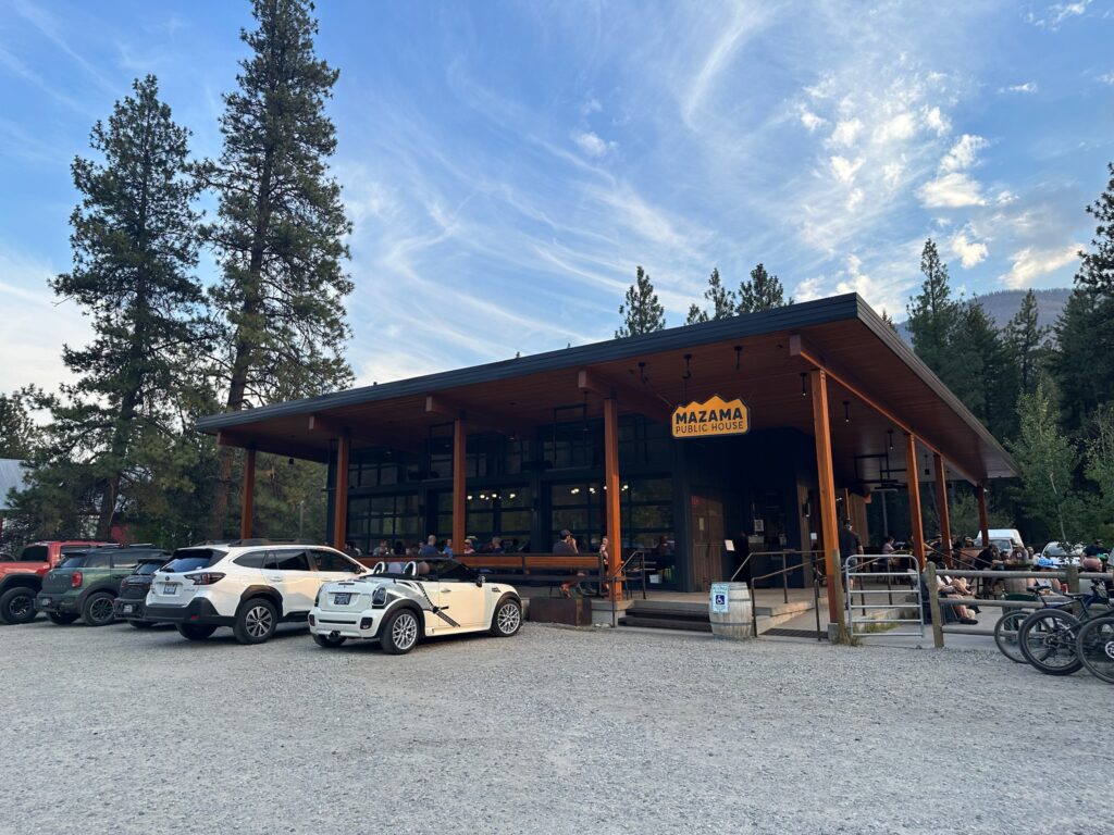 Outdoor dining at the Mazama Public House in summer, surrounded by pine trees and mountain views.