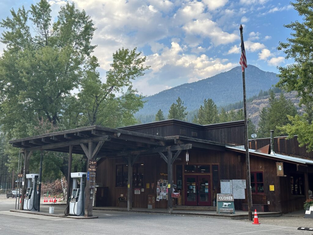 The Mazama Store in Mazama, Washington, surrounded by pine trees with outdoor seating and mountain views.
